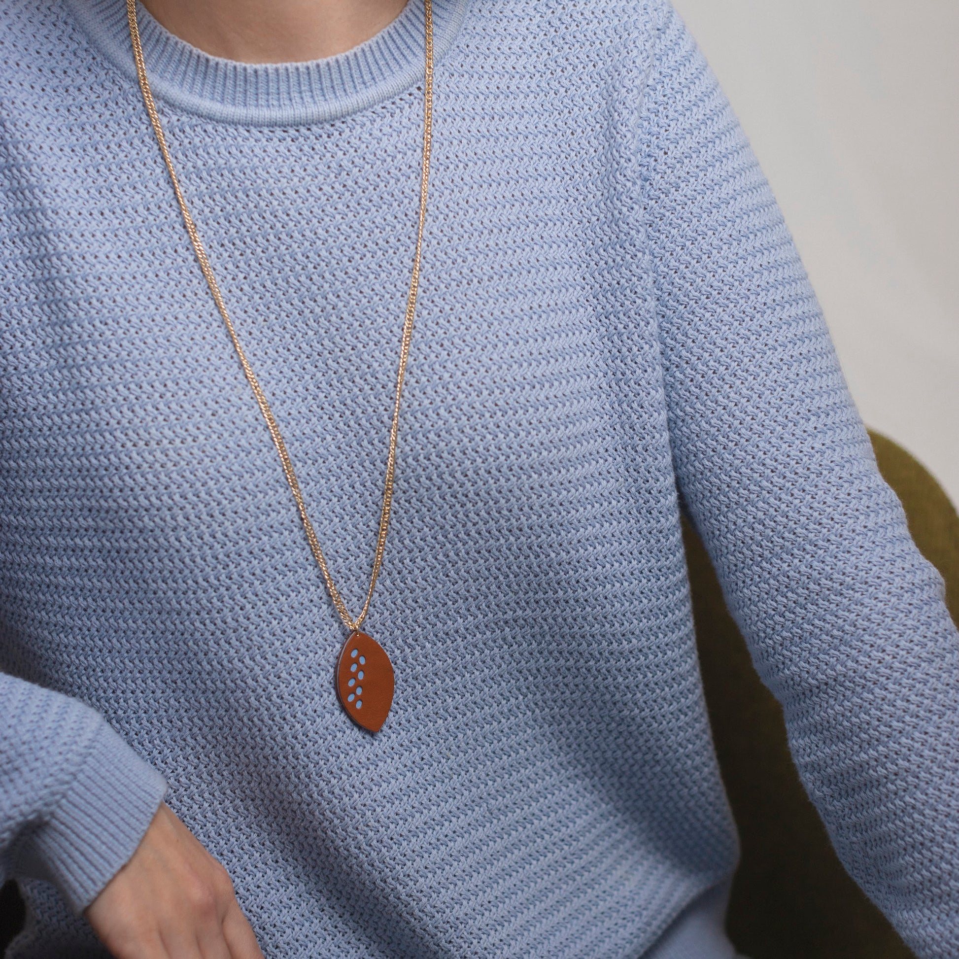 Collier long doré avec pendentif en cuir marron et détails dorés